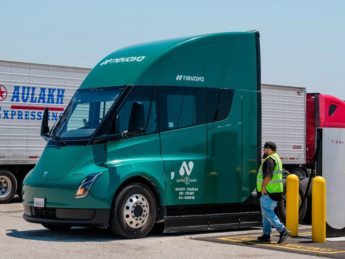 Green Nevoya electric truck plugged in at a charging bay
